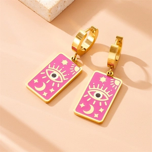 Golden eye and moon star rectangle pendant earrings on a beige stone platform