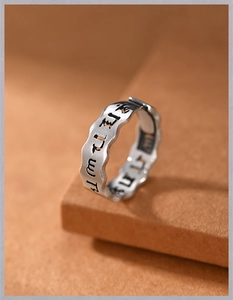 Detailed view of vintage silver ring with wavy edges and carved Sanskrit characters