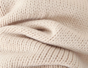 Macro shot of beige thick knit fabric texture showing premium soft knitted material