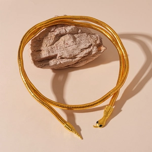 Detailed close-up of flexible golden snake chain necklace with black crystal eyes on rock