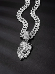 Detail of silver Cuban chain necklace with iced-out lion head crown pendant on black fabric
