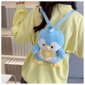 Detail view of the soft blue plush penguin backpack with floral bib on a person back