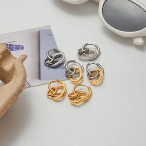 Flat lay di orecchini a cerchio in oro e argento con accessori su sfondo bianco
