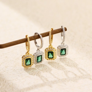 Macro detail of luxury emerald earrings with micro-pave diamonds in gold and silver finish