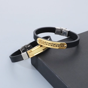 Detail of black leather bracelets with Greek key and grid patterns on gold metal plates