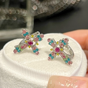 Macro shot of colorful rhinestone-encrusted cross earrings on white velvet display