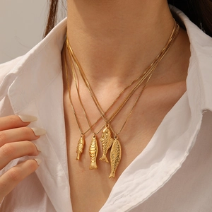 Layered gold stainless steel necklace featuring four unique fish pendants on a model