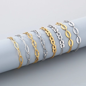 Detail shot of assorted gold and silver geometric chain bracelets on a blue pedestal
