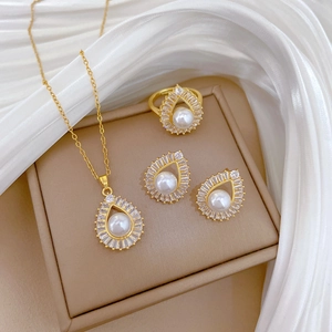 Elegant gold teardrop pearl jewelry set including necklace, ring, and earrings on silk