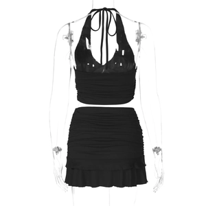 Detail of black halter v-neck crop top and mini skirt with ruffle trim on mannequin
