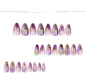 Détail de faux ongles courts en amande avec motifs de lotus violets aquarellés