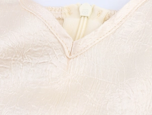 Dettaglio ravvicinato del tessuto satin champagne con zip invisibile e scollo a V fine