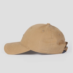 Detail view of khaki cotton baseball cap showing adjustable strap and small woven logo tag