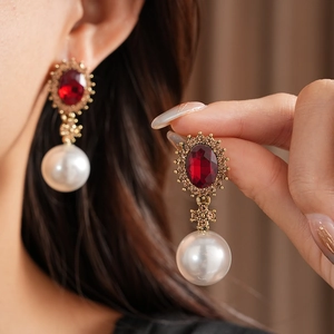 Détail de boucles d'oreilles vintage avec pierres rouges et perles blanches sur modèle