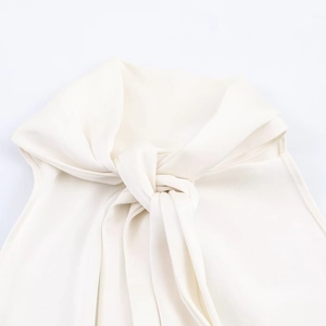 Détail du haut sans manches blanc avec col drapé élégant et texture en satin soyeux