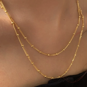 Double-layered gold chain necklace with metallic beads shown on female model