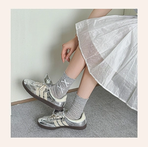 Close-up of metallic silver sneakers with lace trim stripes and Wales Bonner text