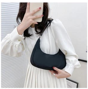 Classic black nylon crescent underarm bag shown in a mirror selfie with a pleated skirt