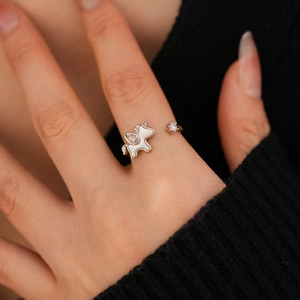 Detailed view of an adjustable gold unicorn ring with zircon and white enamel on a finger