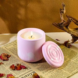Nahaufnahme einer brennenden rosa Duftkerze mit Deckel auf Retro-Zeitungshintergrund