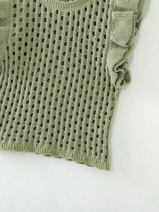 Detailed close-up of light green crochet knit vest with hollow out texture and ruffle sleeves
