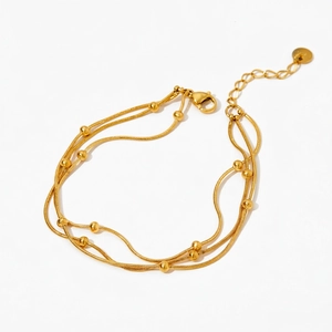 Detail view of gold PVD plated double-layer snake chain bracelet with round beads