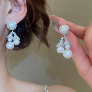 Detailed close-up of fan-shaped silver tassel earrings with white pearls and sparkling zircons