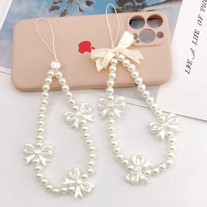 White pearl beaded phone strap with ribbon bow accent on a soft pink phone case
