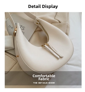 Close-up of off-white crescent underarm bag with gold metal zipper and rivet accents