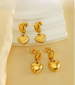 Detailed close-up of textured and smooth 18K gold-plated heart stud earrings on a stand