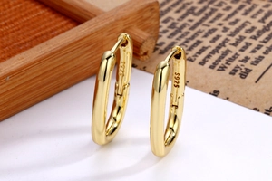 Macro detail of gold-plated U-shaped earrings with S925 hallmark on a classic newspaper