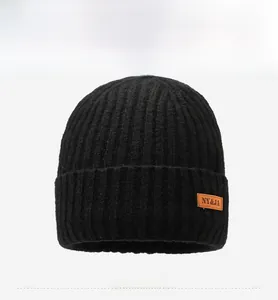 Close-up of black ribbed knit beanie featuring a brown leather decorative label