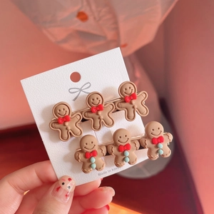 Gingerbread man hair clip set with cute resin dolls on white card against pink background