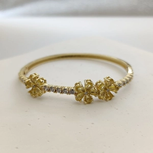 Macro shot of three delicate gold-plated flowers with yellow zircon on a bangle