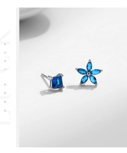 Macro detail of asymmetric s925 silver flower and square blue sapphire stud earrings