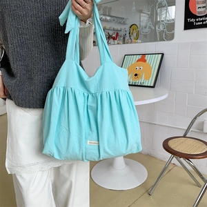 Detail der hellblauen Canvas-Tasche mit Raffungen und gewebtem Etikett im Café-Ambiente