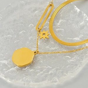Macro shot of layered gold snake chain with star and textured round coin pendants
