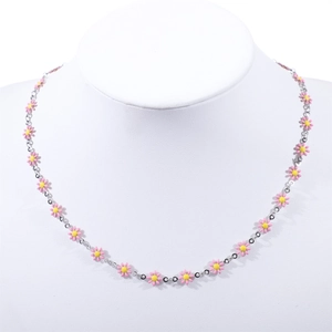 Macro detail of a 18K gold stainless steel necklace with pink and yellow daisy flower charms