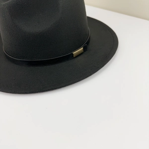 Detail of classic black wool fedora featuring a slim leather band and gold metal buckle
