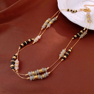 Detail of double-layer agate beaded necklace with grey and black stones on silk background