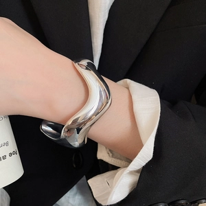 Macro view of silver wave irregular wide cuff bracelet with polished mirror finish