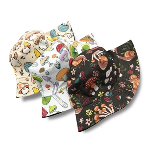 Reversible bucket hat with mushroom patterns in beige, white and black colors