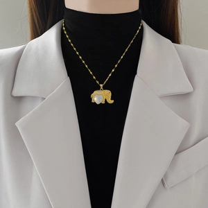 Elegant gold elephant necklace with white heart stone on model with blazer