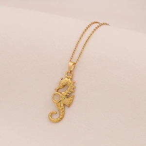 Detailed macro view of gold seahorse pendant with white gemstone on O-chain necklace