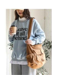 Detail of a brown canvas messenger bag worn by a model in a casual outfit context