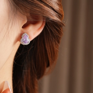 Close-up of hulu stud earring with purple teardrop gemstone and micro-pave crystals