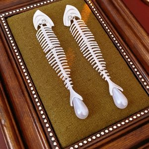 Macro detail of silver fishbone earrings with sparkling zircons and white pearl drops