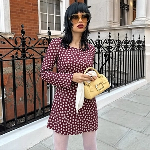 Street style shot of a burgundy long-sleeve polka dot dress with retro round neckline