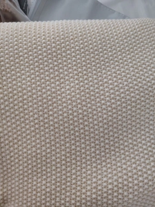 Close-up of cream chunky knit texture showing soft yarn weave on a Nordic sofa blanket