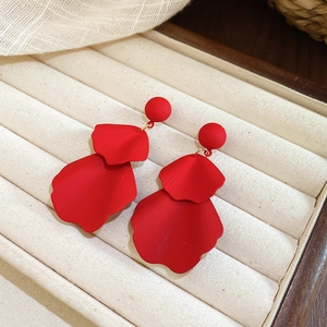 Detail of red matte petal earrings with layered design in a beige jewelry tray